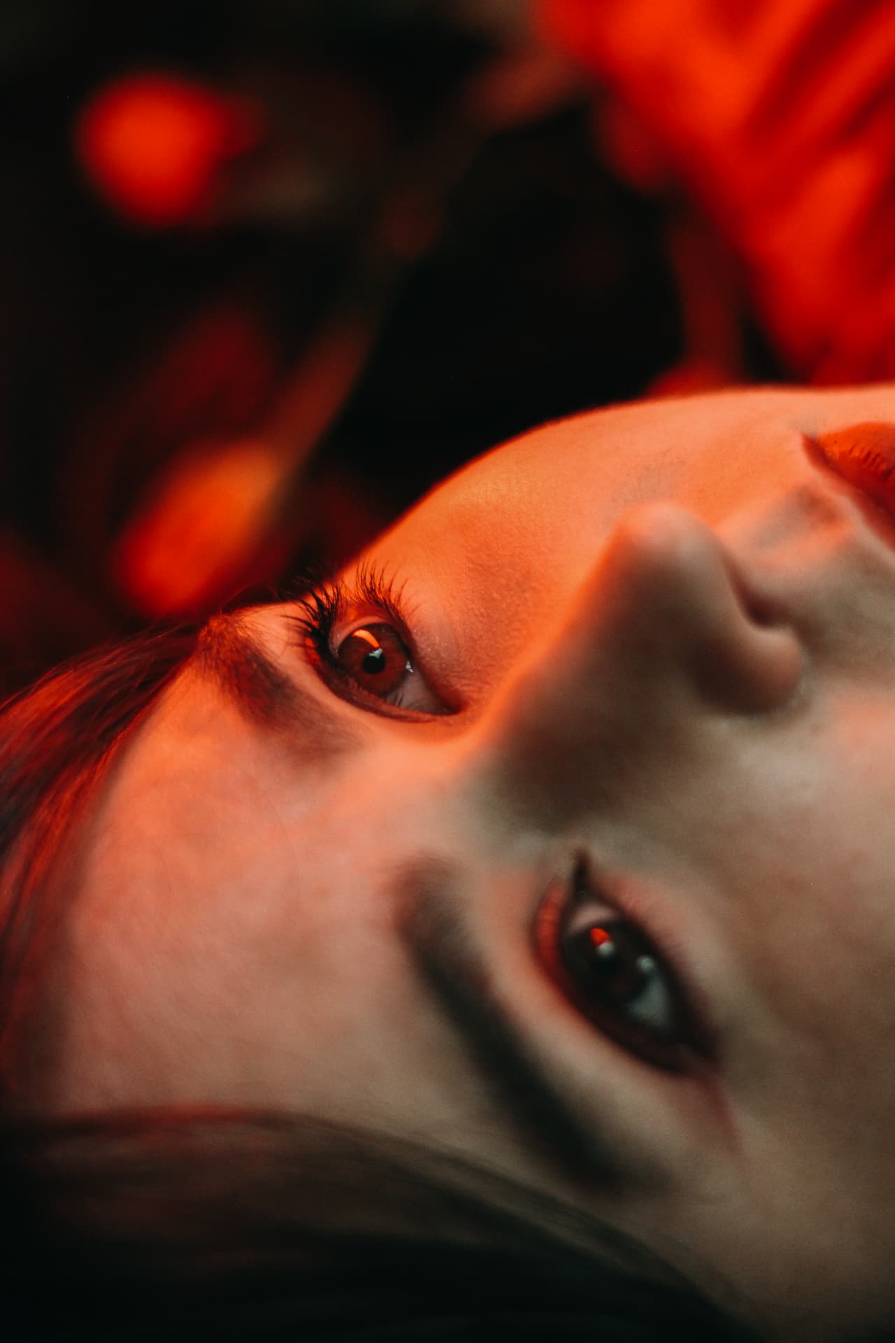 Close-up portrait of a woman's face lit by warm red light