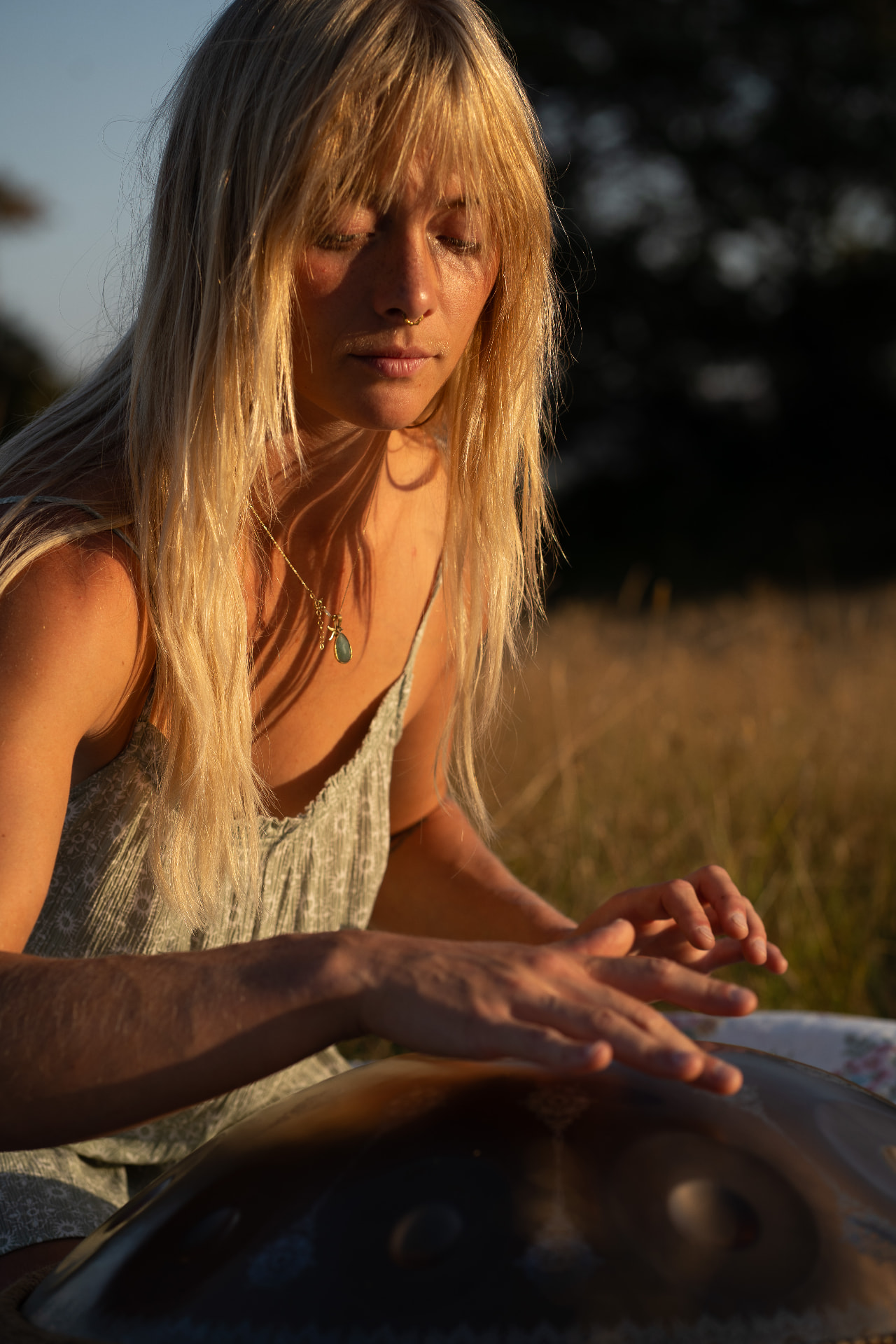Blonde woman playing a singing bowl in warm evening light