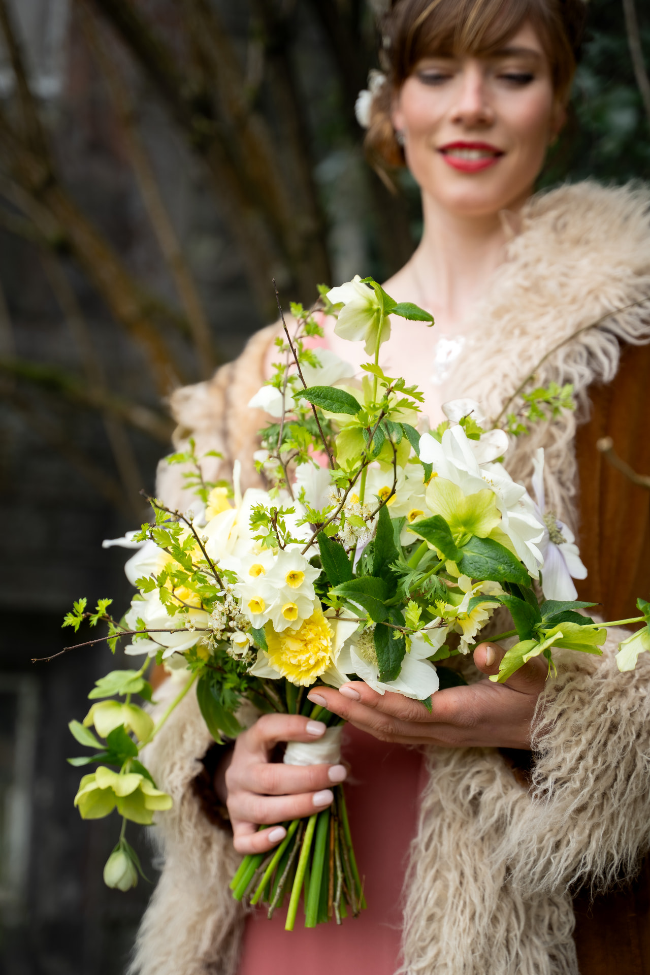 Woman in a fur-trimmed coat holding a spring floral bouquet