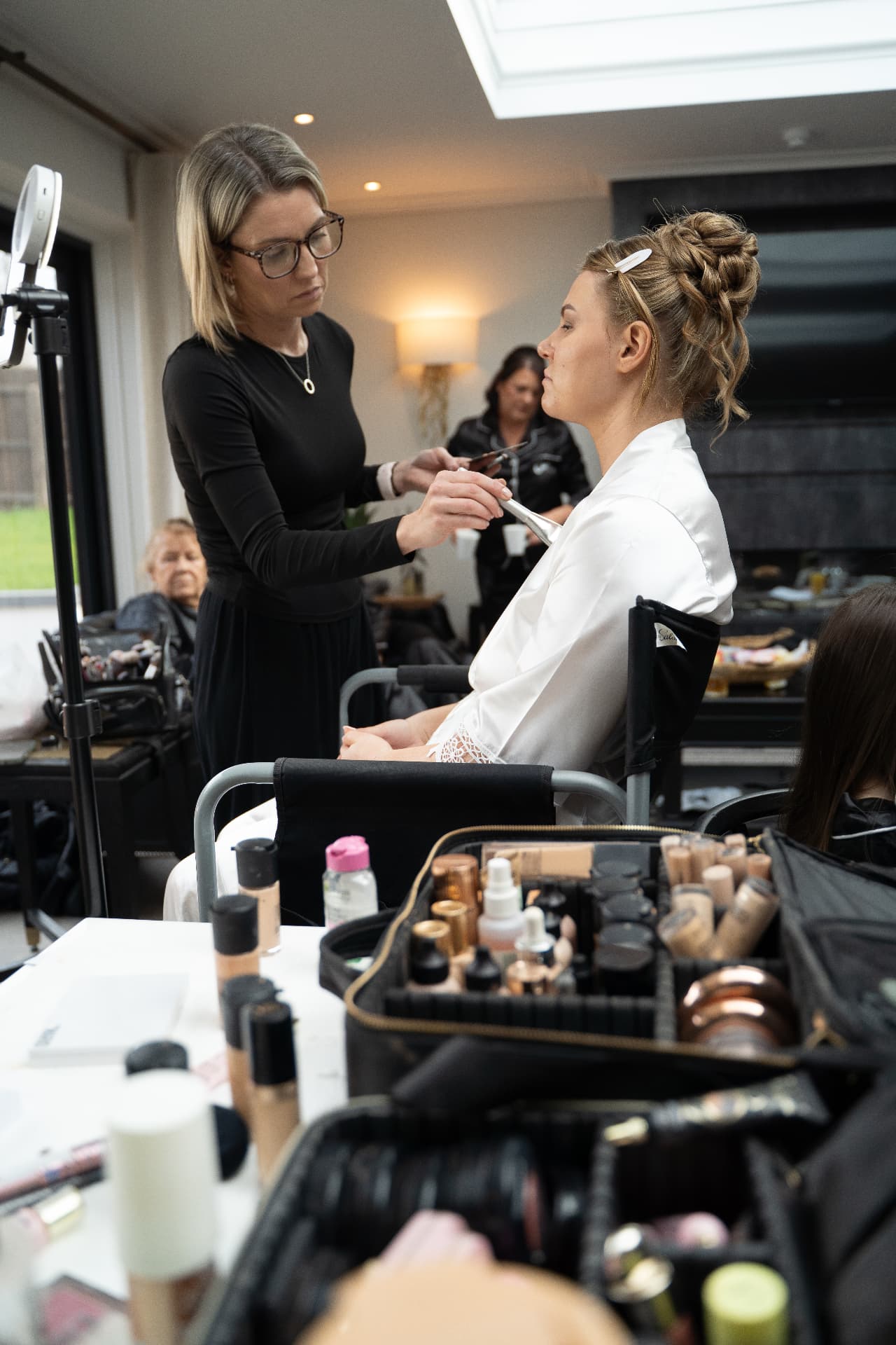 Makeup artist applying makeup to a bride before the ceremony