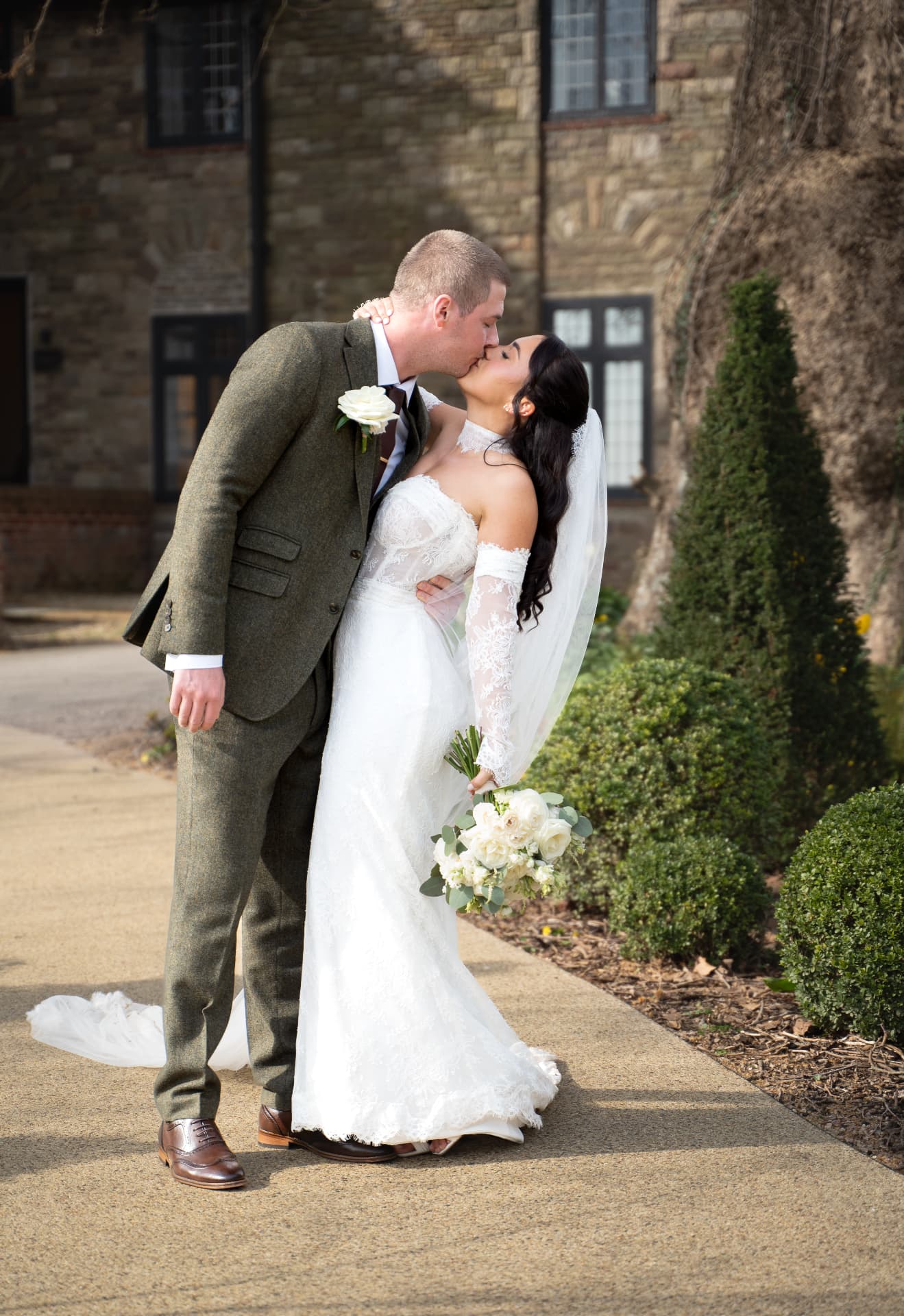 Bride and groom sharing a kiss outside a stone country building